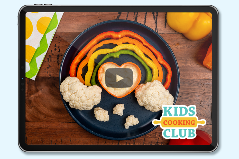 rainbow made with colorful peppers and cauliflower as clouds with a heart-shaped bowl filled with dip- logo Kids Cooking Club