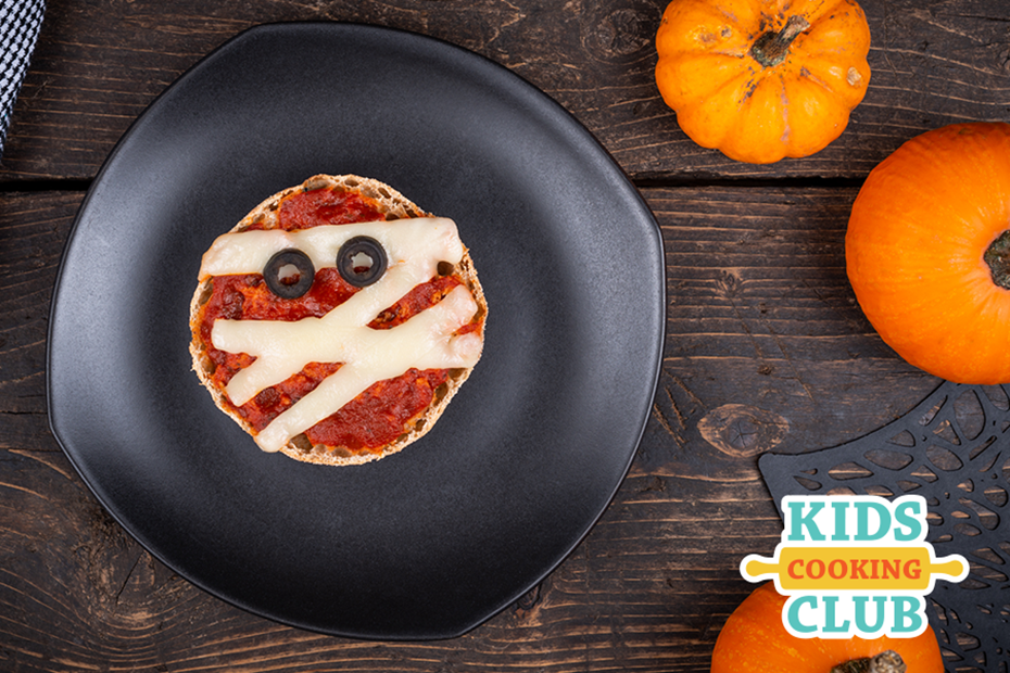 pizza mummies made with an english muffin on a plate with pumpkins around