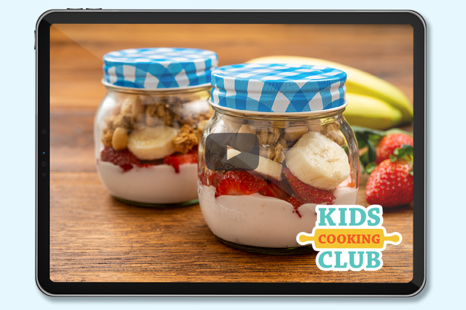 strawberry and banana parfait in a jar on a table. Logo: Kids Cooking Club